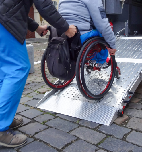 Rollstuhlfahrer wird mit Rampe in ein Fahrzeug geholfen – Rollstuhlfahrten von Vestische Fahrdienste